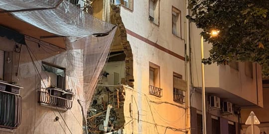 Emergency services at night around a partially collapsed building in Badalona, with debris on the street.