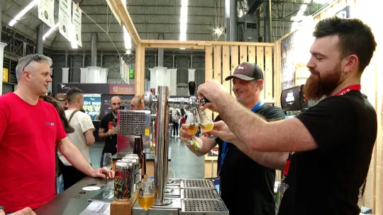 People tasting craft beer at a lively festival with many taps and bottles on display in Barcelona