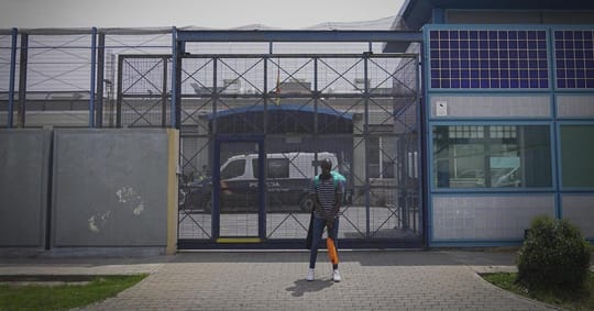 Exterior view of the Centre d'Internament d'Estrangers (CIE) in Barcelona's Zona Franca, with a low tower painted blue and wh