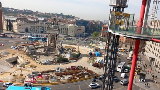 A modern FGC train arriving at a station in Barcelona, with passengers waiting on the platform.