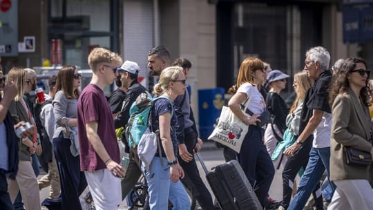 Tourists sitting on stairs and in a hallway of a hotel, looking frustrated.