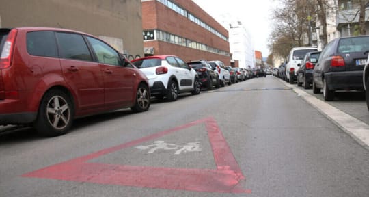 Children walking near a busy road with cars and buildings, showing air pollution haze in the background.