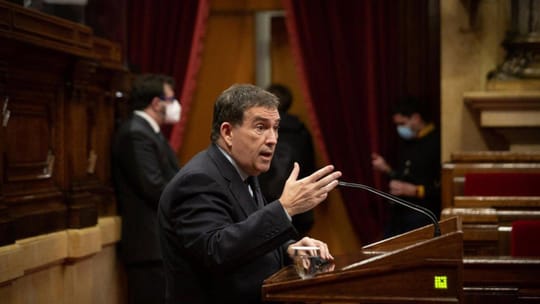 Jaume Alonso-Cuevillas speaking at a political event, with a Junts per Catalunya logo visible in the background.