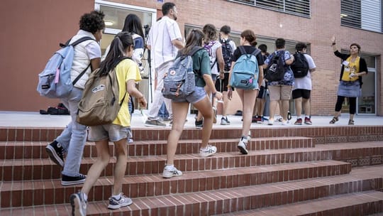Young students in a classroom setting, possibly in El Raval, engaged in learning activities with a teacher or mentor.