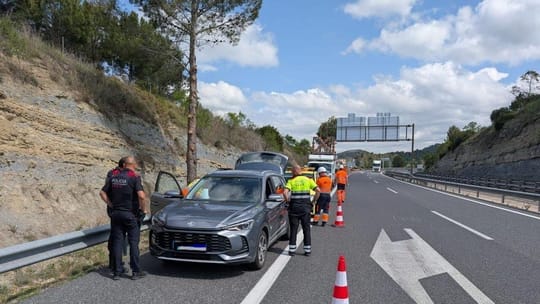 Mossos d'Esquadra police car with flashing lights on the hard shoulder of a motorway at night.