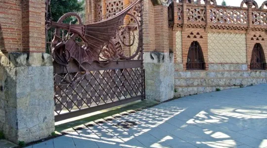 The ornate wrought-iron Dragon Gate designed by Antoni Gaudí at Finca Güell in Barcelona, featuring a dragon sculpture.