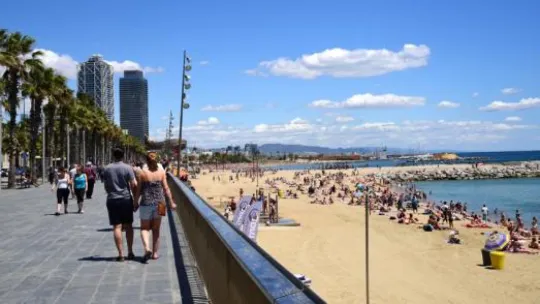 Barceloneta beach in Barcelona with people walking along the shore and the sea in the background