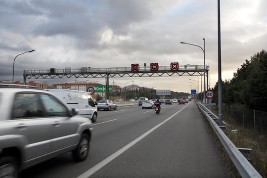 Heavy traffic on a multi-lane motorway leaving Barcelona, with many cars heading out of the city under a clear sky.