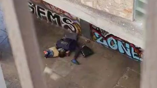 A narrow, dimly lit street in Barcelona's Raval district at night, with some rubbish visible and a sense of unease.