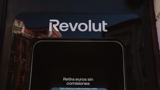 Revolut logo on a modern building facade in Barcelona, with people walking past.