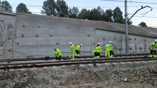 A Rodalies train travelling on tracks through a rural landscape in Catalonia.