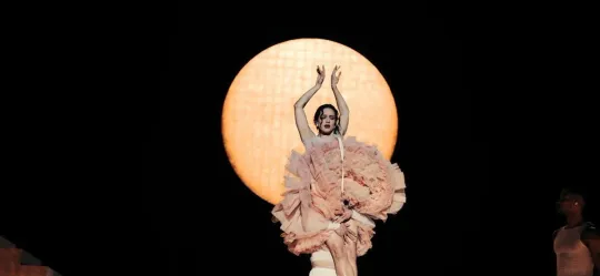 Rosalía performing on stage with dancers and elaborate lighting during her Lux tour.