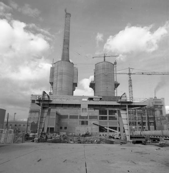 The three tall, cylindrical chimneys of the former Besòs power plant stand against a clear sky.
