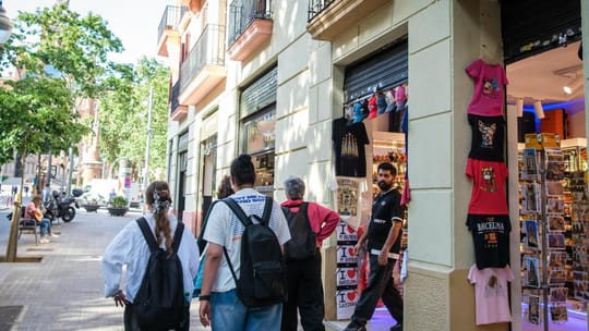 Avenida Gaudí in Barcelona, showing the Sagrada Família in the background and various shopfronts along the street.