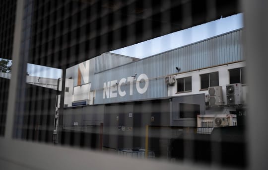 Tenneco factory building in Badalona Sud industrial estate with residential buildings in the background under a clear sky.