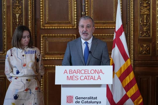 A diverse group of adults in a classroom setting, actively participating in a Catalan language lesson.