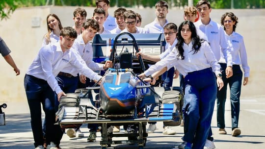 Catalan university students working on a Formula Student race car in a workshop.