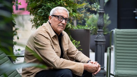 Javier Melero, a man with glasses, speaking at a podium with a book titled "Crímenes decentes" visible.