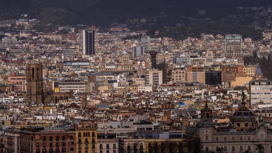A panoramic view of Barcelona's skyline with modern buildings and the Mediterranean Sea in the background, symbolising econom
