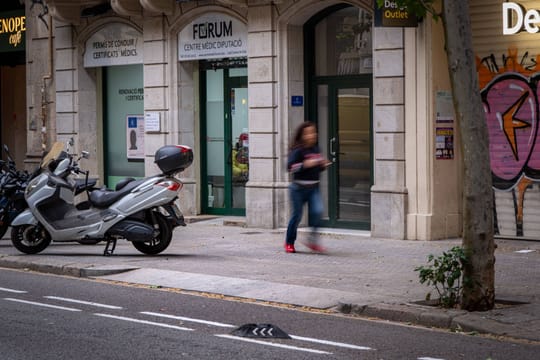 A street in Barcelona's Eixample district with a disused vehicle access point (vado) on the pavement, showing a gap where a t