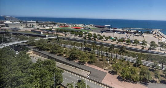 Aerial view of the Fòrum marine platform in Barcelona, showing a large, open concrete area next to the sea.
