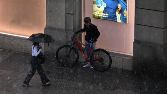 Hailstones covering a street in Barcelona after a severe storm, with wet pavements and buildings in the background.