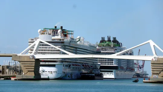 Cruise ships docked at the Port of Barcelona with the city skyline in the background