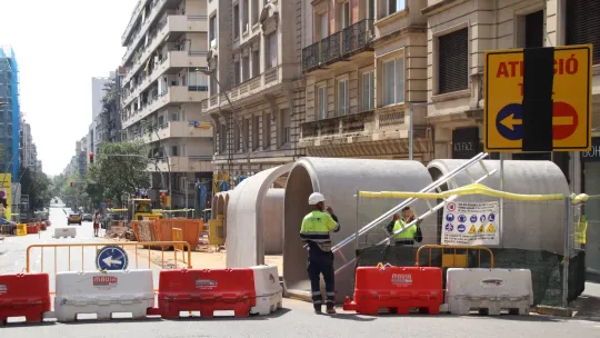 Construction machinery and barriers on a city street, indicating road closure for underground works.