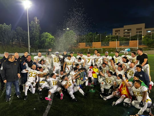 Barcelona Pagesos American football team celebrating their victory on the field with a trophy.