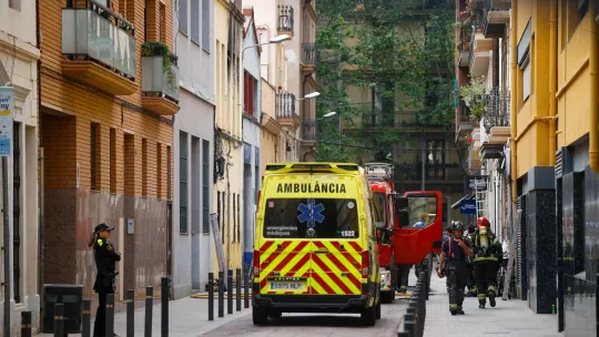 Emergency services, including firefighters and ambulances, at the scene of a building explosion on a street in Barcelona's Po