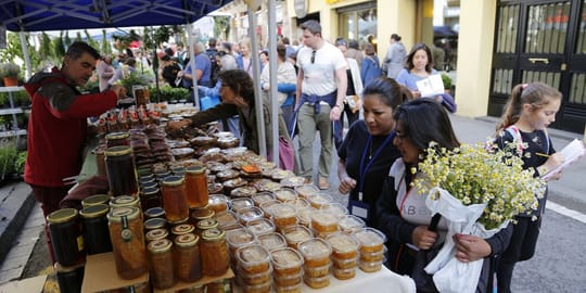 Stalls selling herbs, honey, and artisan products at the Sant Ponç fair on Carrer de l'Hospital in Barcelona.