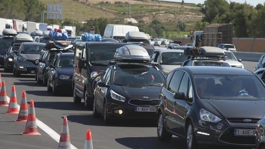 Traffic jam on a multi-lane motorway in Barcelona metropolitan area during a holiday exodus, with many cars visible.