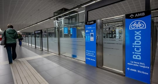 A modern Bicibox secure bicycle parking facility with multiple bikes stored inside, located near a public transport hub.