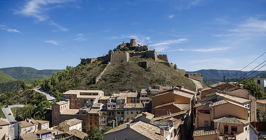 Historic Cardona Castle, a medieval fortress with a tall tower and stone walls, under a clear sky.