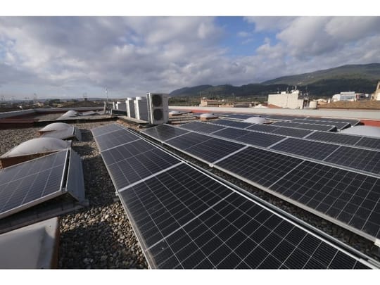 Solar panels on a residential rooftop in Barcelona with city buildings in the background