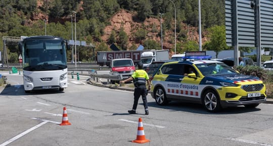 Mossos d'Esquadra officers inspecting a large lorry at a service area on a motorway in Catalonia, with other vehicles in the 