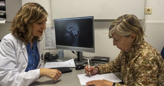 A woman in her 70s, looking thoughtful, sits in a medical office, representing patients facing diagnostic delays.