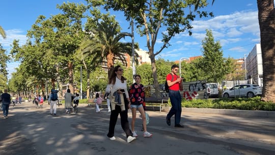 People walking, cycling, and using the tram along Avinguda Diagonal in Barcelona, showing green spaces and modern architectur