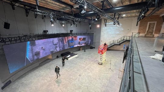 Interior view of Espai Diagonal, showing a large, modern event space with a high ceiling and a large LED screen.