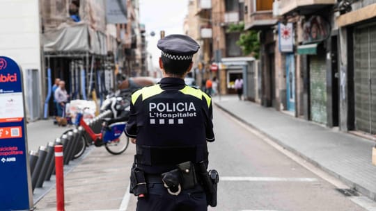 A 'Closed' sign on the shuttered entrance of a bar in a city street, with a police vehicle visible in the background.