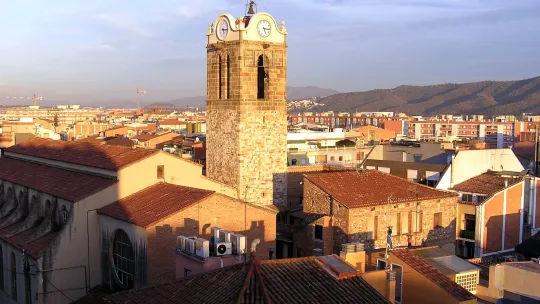 A panoramic view of Mollet del Vallès, showing a mix of historic buildings, green spaces, and residential areas under a clear