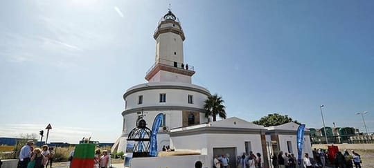 Llobregat Lighthouse at the Port of Barcelona, a cylindrical building with a quadrangular tower and glass dome, with ships in