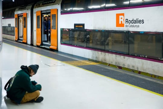 A Rodalies R2 Sud train at a station platform, with passengers waiting or boarding.