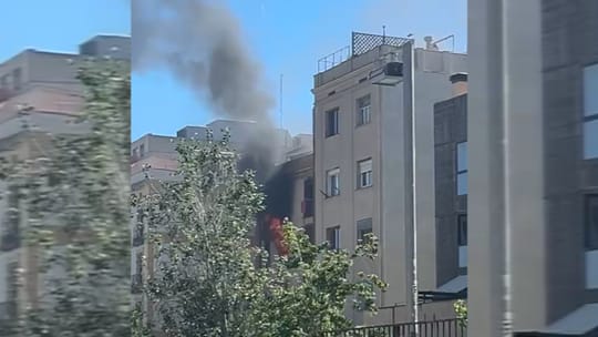 Firefighters respond to an apartment fire with smoke billowing from balconies on Carrer Nou de la Rambla in Barcelona's Raval