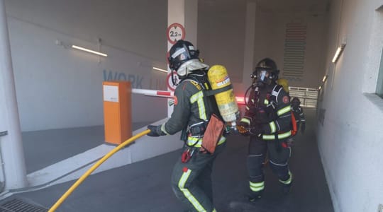 Emergency vehicles and personnel gathered outside Torre Mapfre during a fire drill, with the tall building in the background.