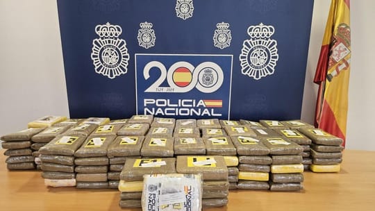 Police officers inspecting packages of cocaine with an F-1 logo inside a car's hidden compartment.