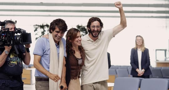 Film crew setting up equipment at a cruise terminal, transformed to look like an airport, for a dramatic reunion scene.