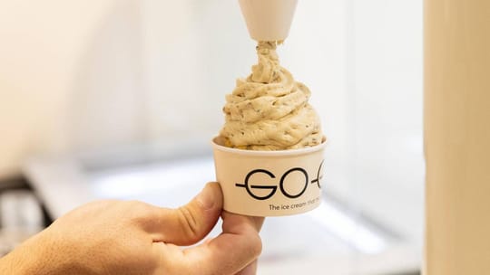 A Go-Go ice cream machine with Gaudí-inspired design elements, dispensing custom ice cream into a cup.