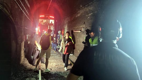Emergency services personnel and volunteers evacuating a metro train in a dark tunnel during a drill in Barcelona.