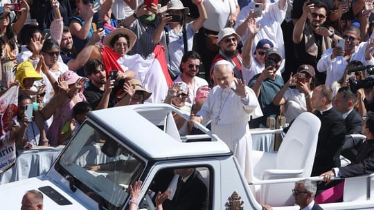 The Popemobile, covered by a tarpaulin, being transported by a crane from a military aircraft at El Prat Airport, escorted by